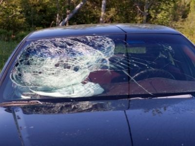 view of the front windshield of a blue car with the glass heavily cracked