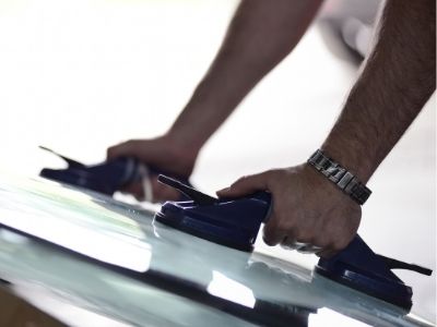 autoglass technician replacing a car windshield using suction cup handles