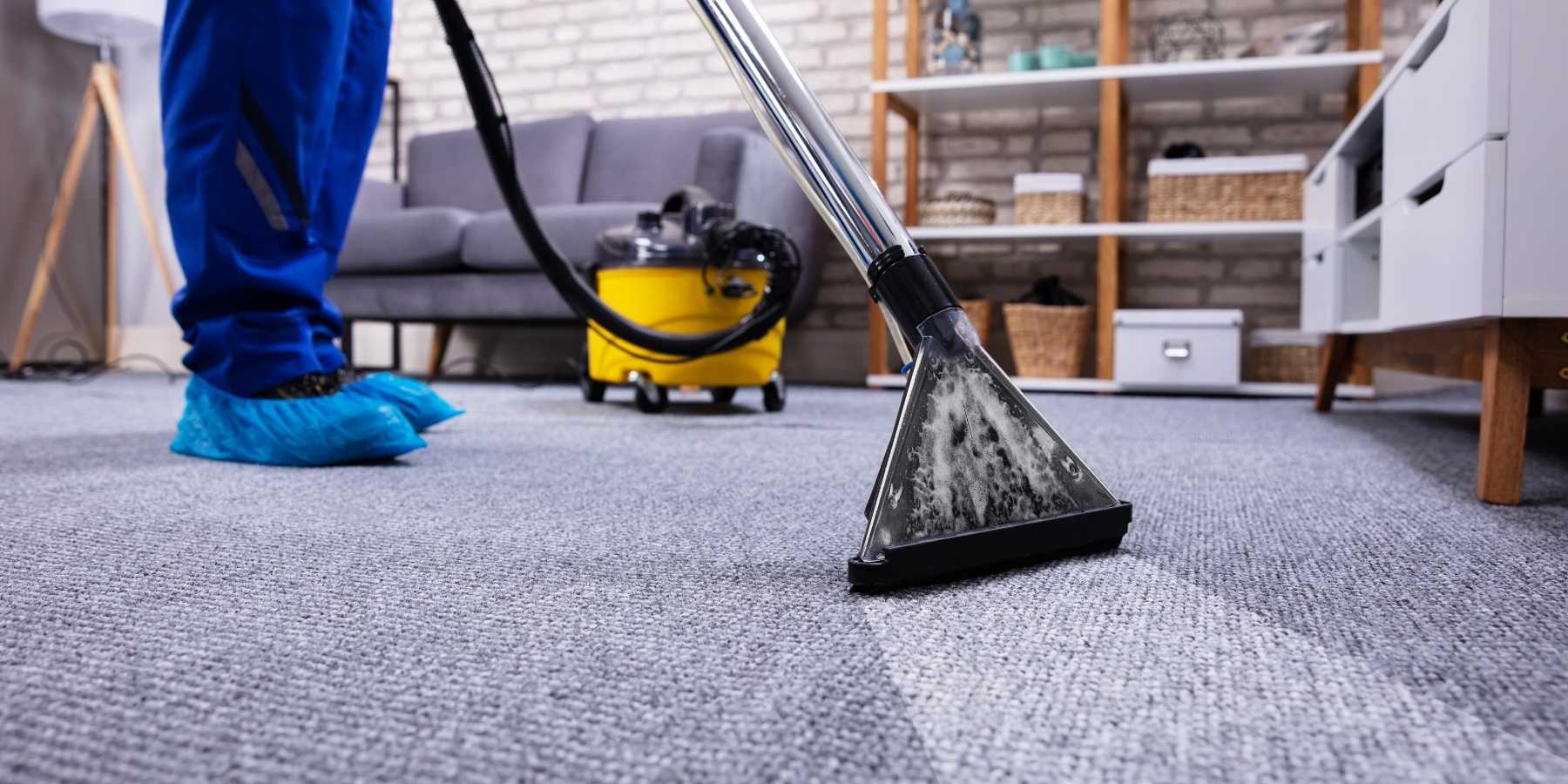 man cleaning a carpet inside a home with a commercial vacuum