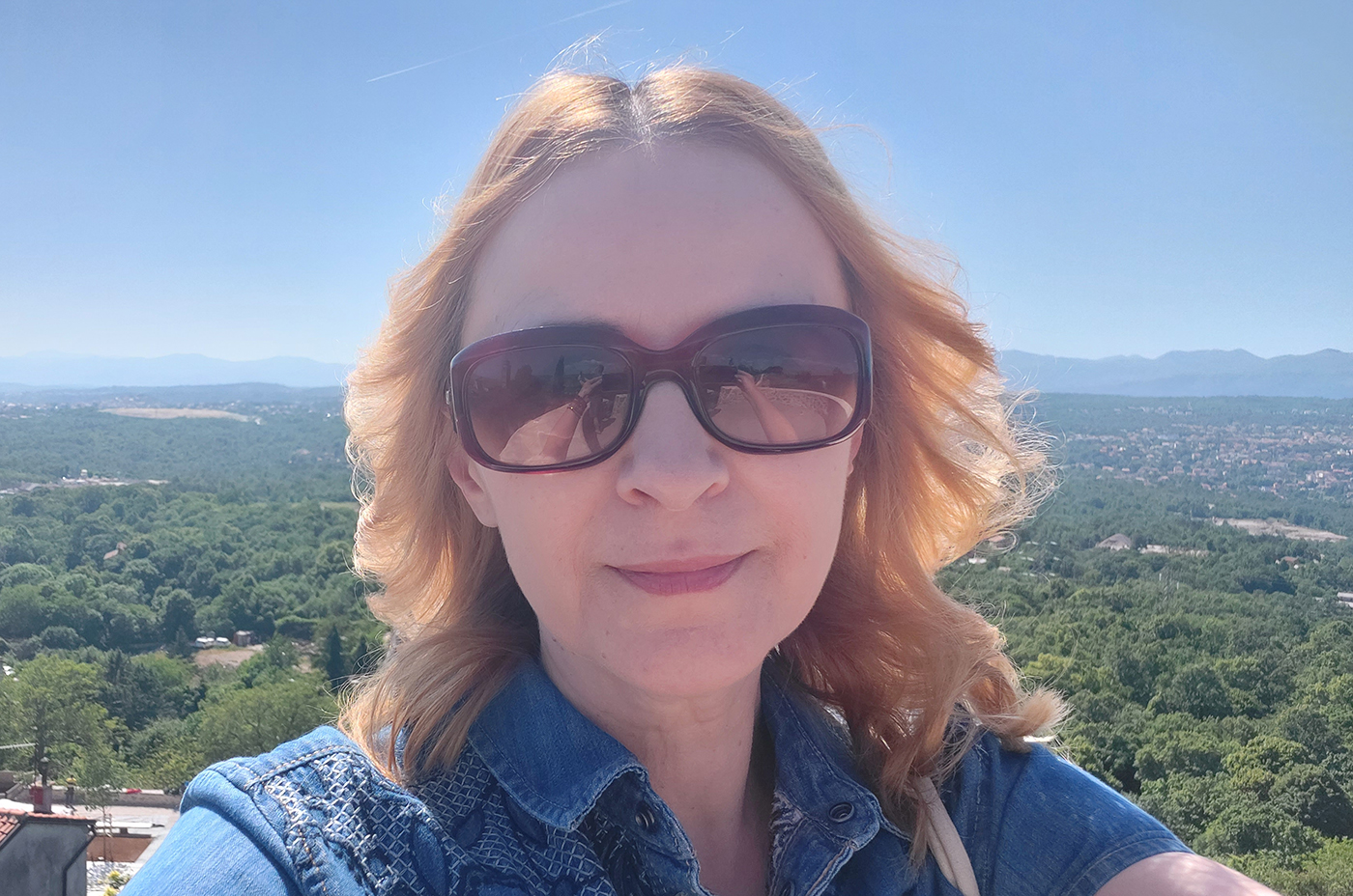 žena koja ima rak dojke u plavoj haljini iza nje pogled s prekrasnim plavim morem