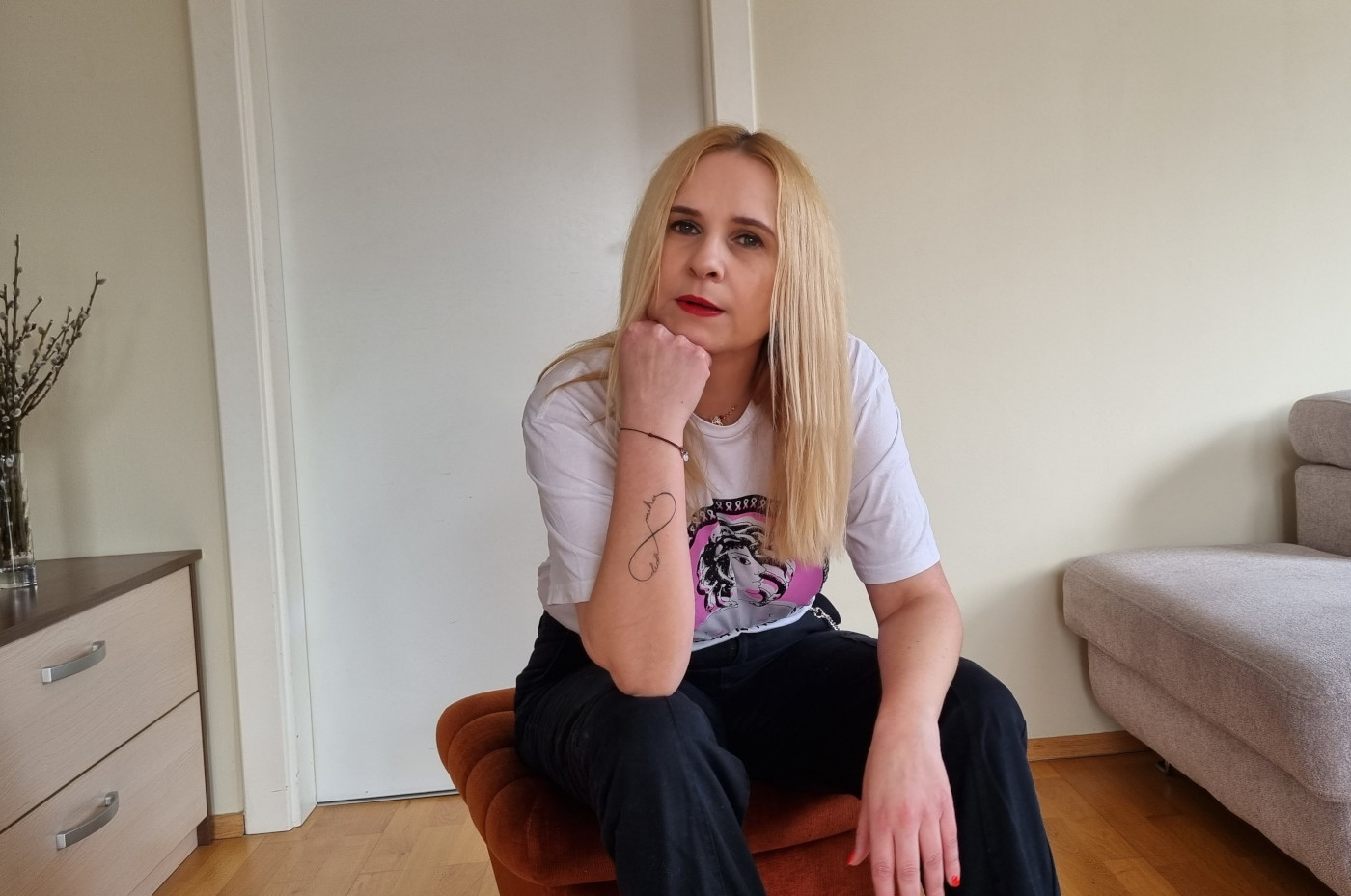 žena oboljela od raka dojke sjedi na tabureu i zamišljeno gleda čekajući nalaze punkcije
