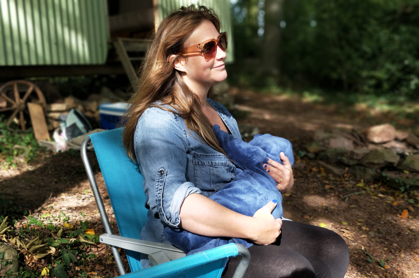 žena u plavoj košulji sjedi na plavom stolcu i doji bebu prije dijagnoze raka dojke