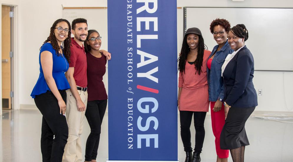 Six Relay students posing around a Relay GSE banner.