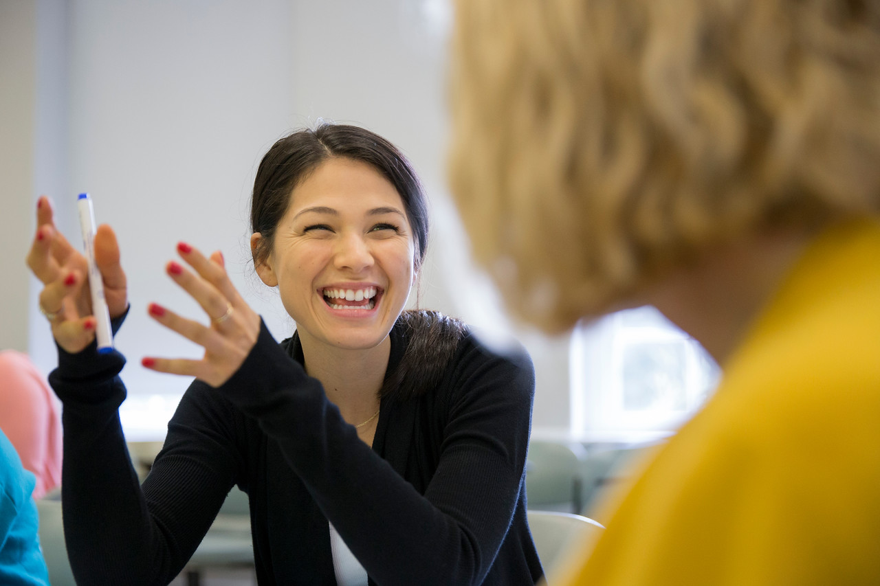 Two women talking, one is grinning and gesturing.