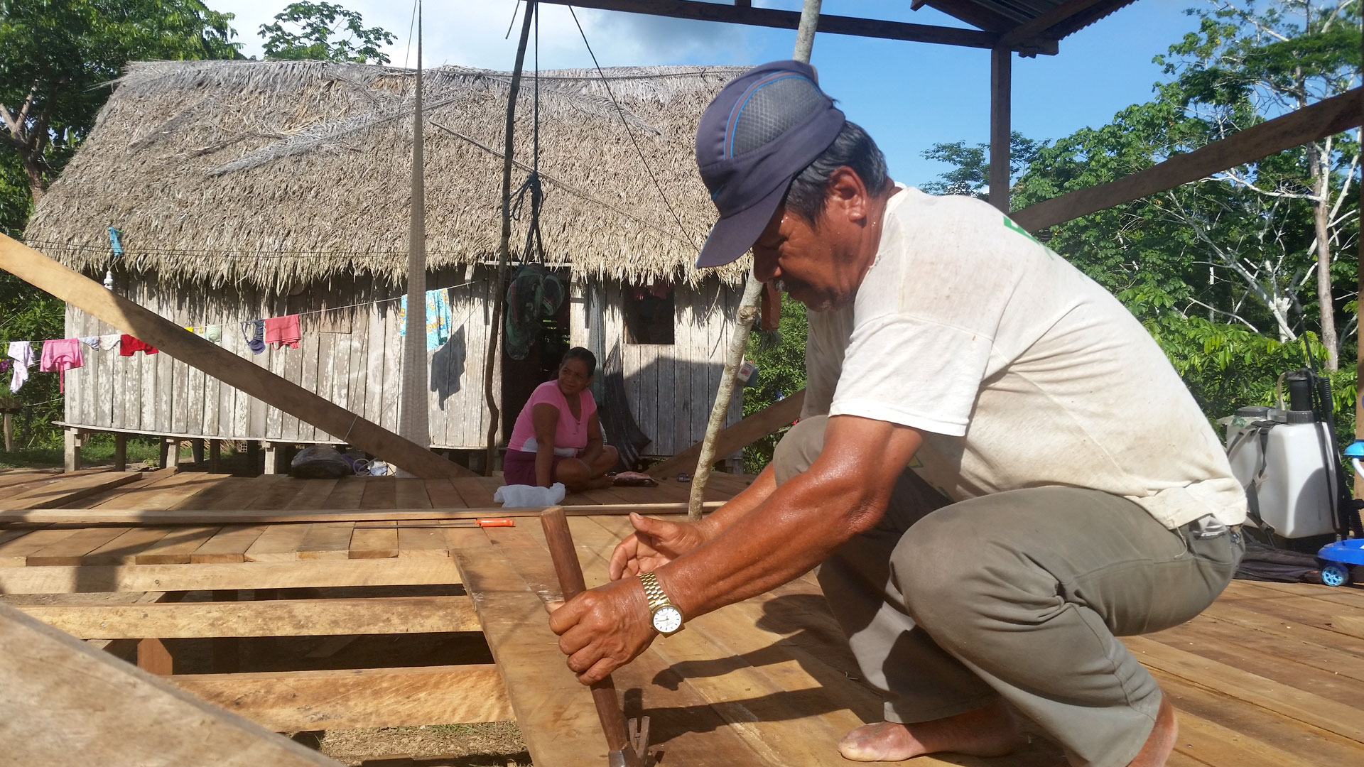 A Peruvian man with a hammer repairing wooden flooring