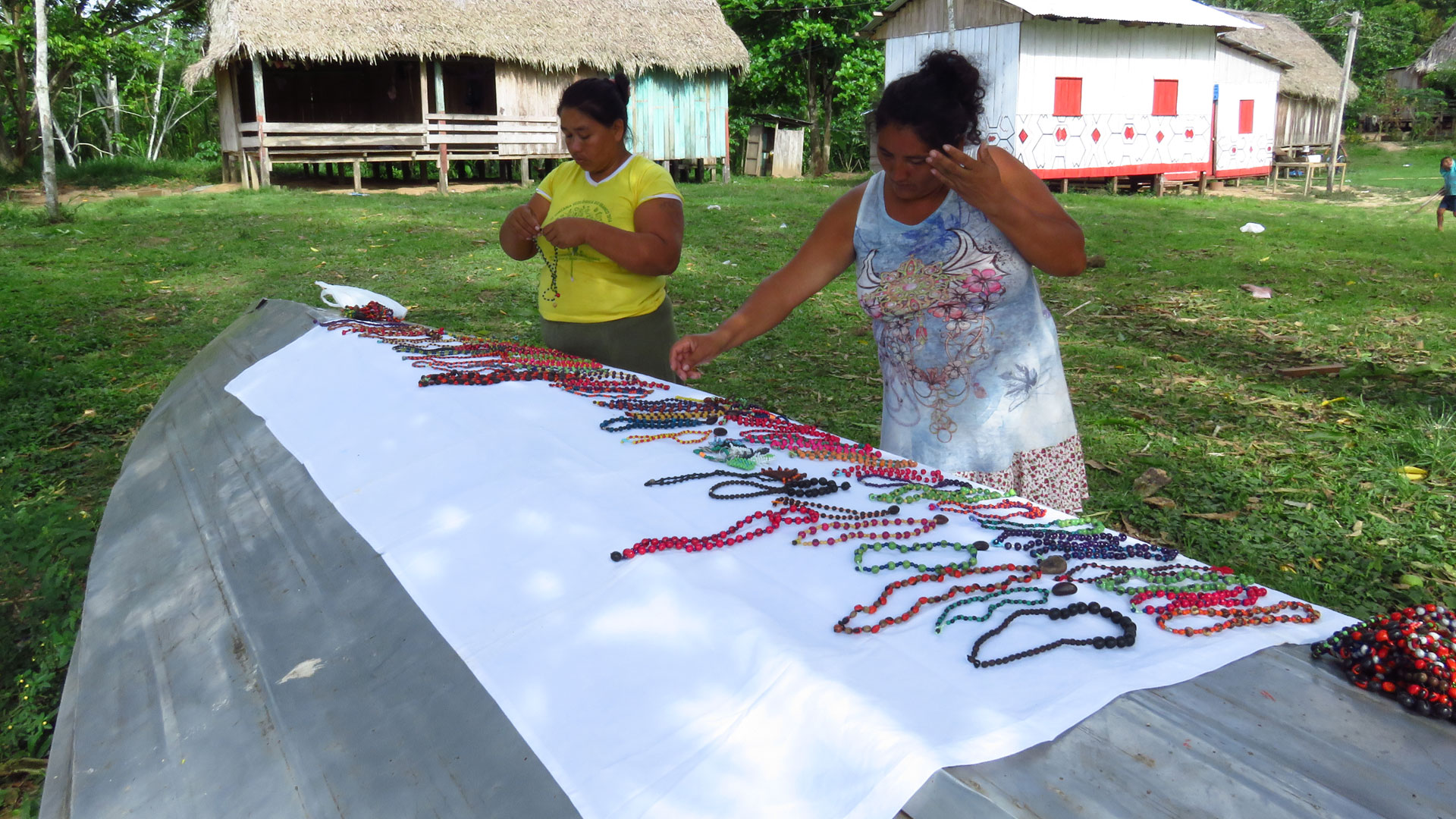 Two women laying our homemade beaded jewellery on an upside down boat