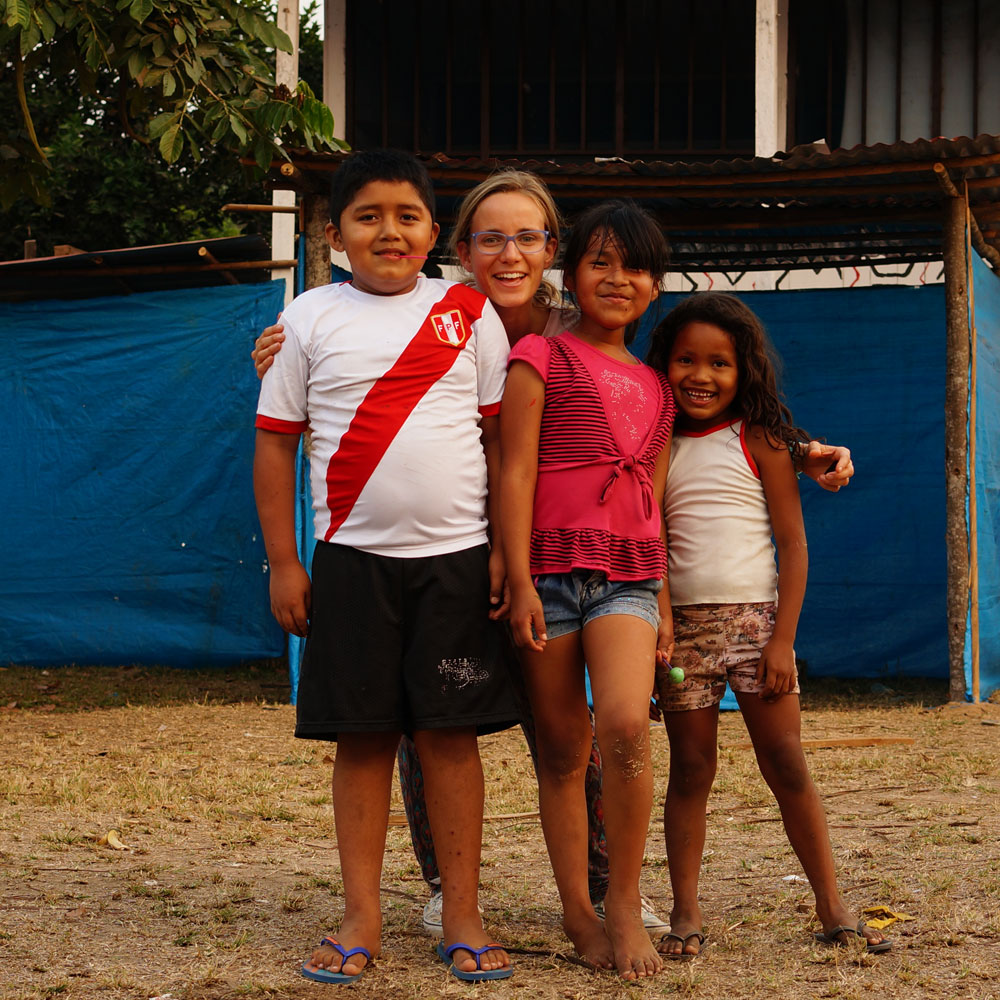 Young children from the community posing with a project worker