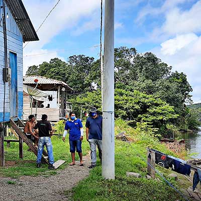 A group of indigenous men meeting next to a wooden building on the riverbank