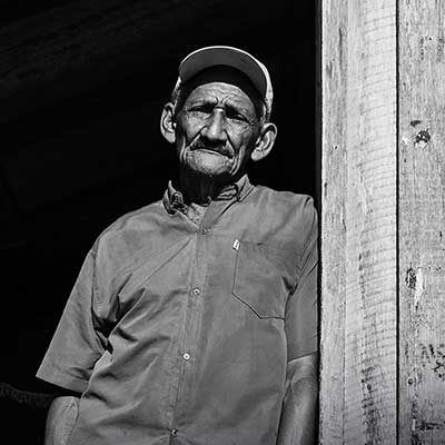 A black and white image of an elderly Brazilian man standing in a doorway