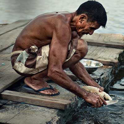 An indigenous Brazilian man preparing fish by the river