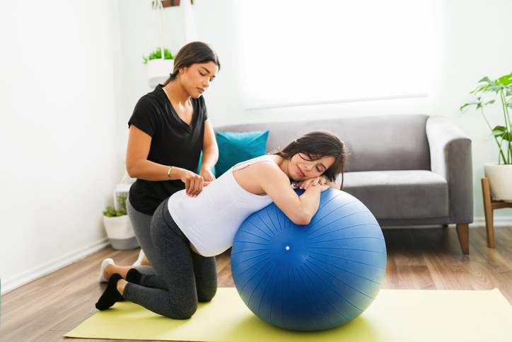 Doula performing a hip squeeze to a laboring woman.