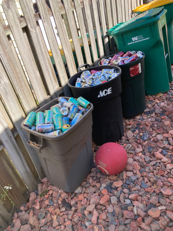 Three large garbage bins filled with empty cans