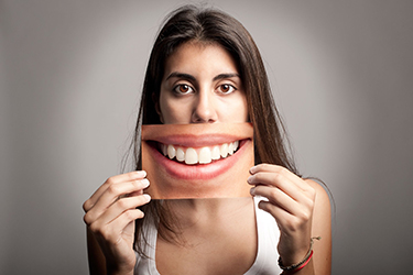 Woman holding smile photo when your happy with the appearance of your teeth, you smile more.