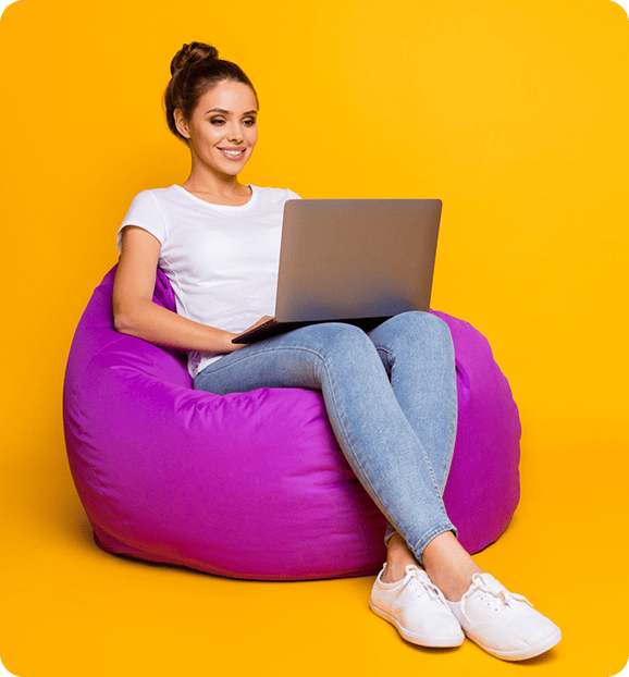 Woman sitting on chair with laptop on her lap.