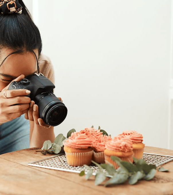 Woman taking pictures of cupcakes.
