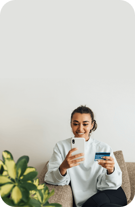 Woman holding a credit card and a phone.