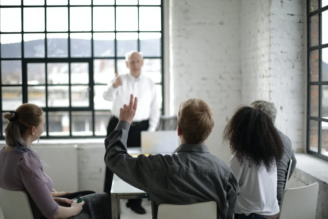 Man raising hand to ask question in a meeting