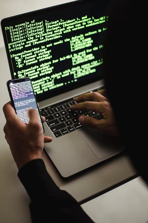 Person using laptop and phone for coding