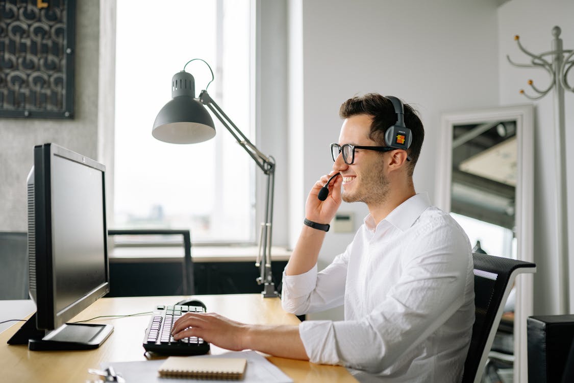 Smiling man typing on keyboard and looking at monitor screen