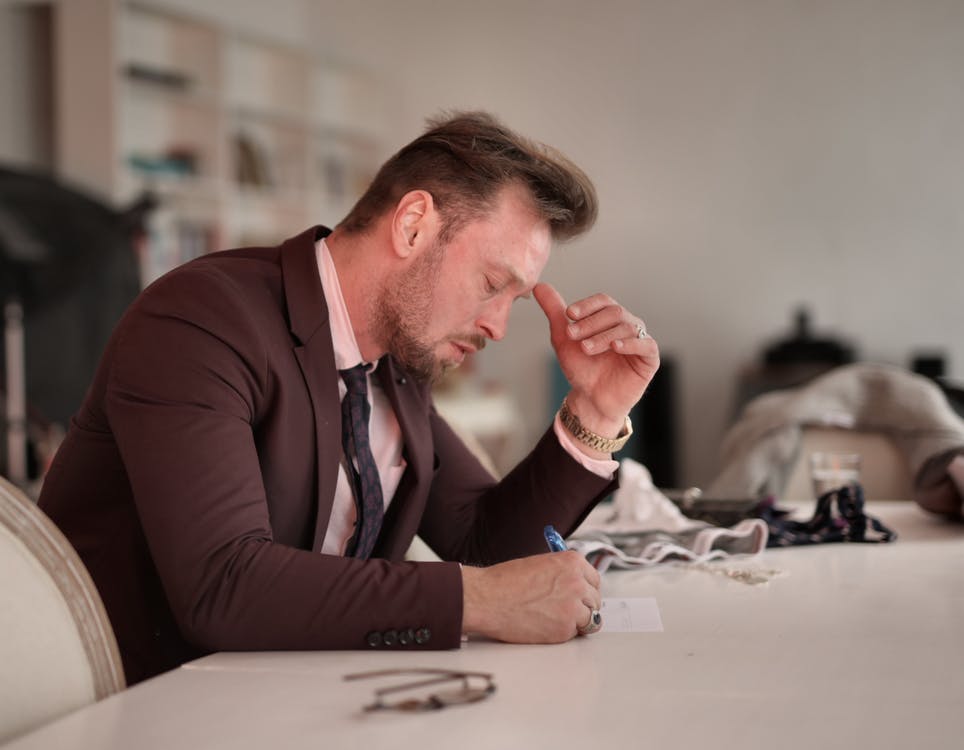 Man writing on paper with his eyes closed
