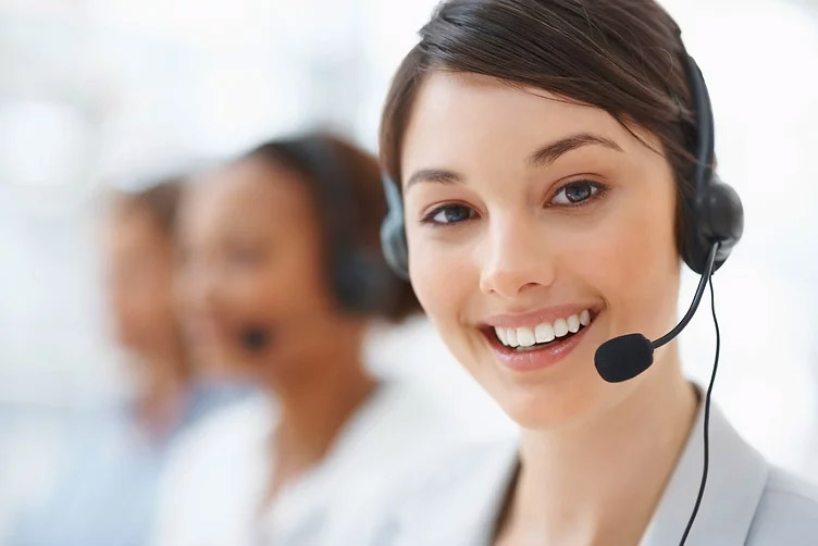 A young female receptionist with a phone headset on smiling.