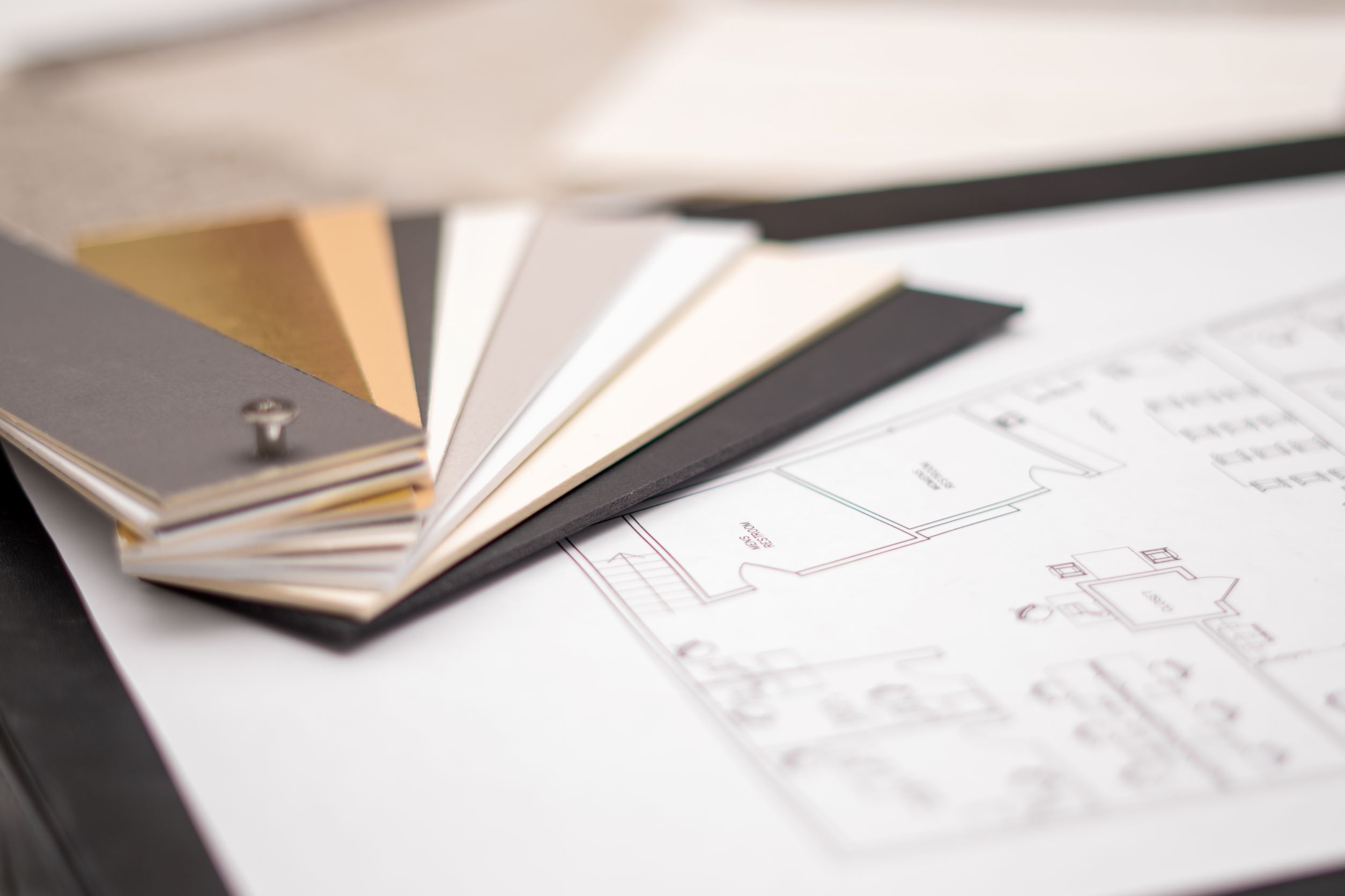 A book of fabric material swatches placed on top of a sheet of paper with specifications for a design on it.
