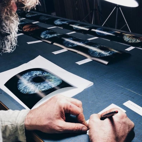 Our photo technician is sitting at a table, hand editing copies of iris photos.