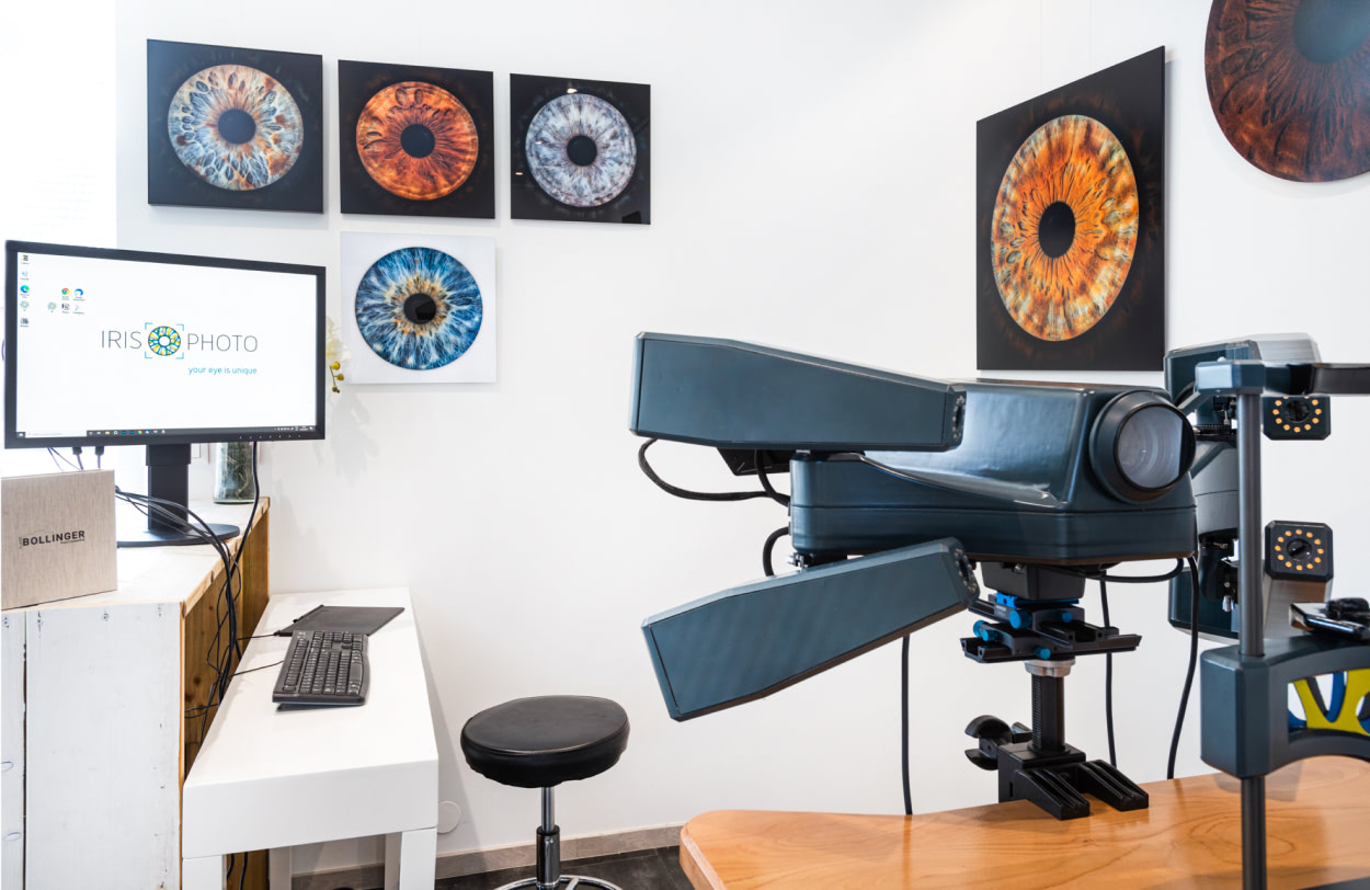 A close-up of the Eyedentity camera system in the studio. There are several framed iris photos hanging on the walls.