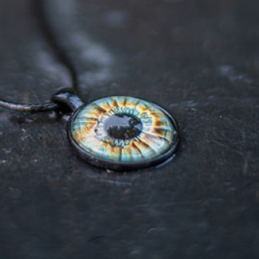 A single blue iris with orange rings protruding from the center black iris on a black background.