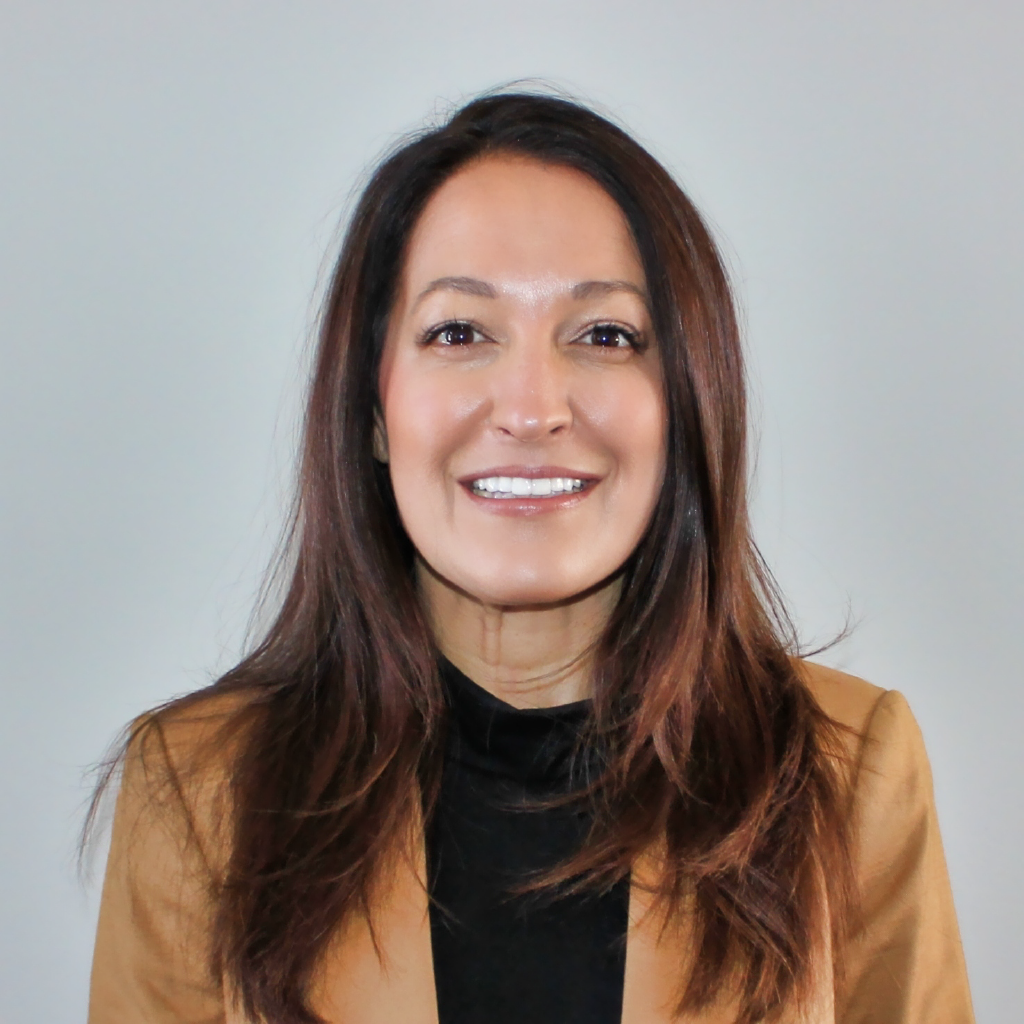 A woman smiles at the camera against a gray background.