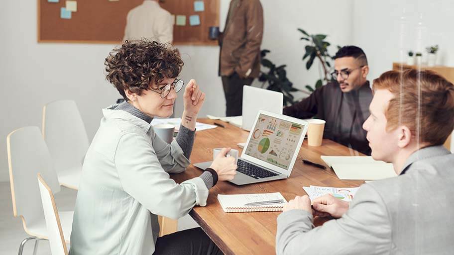A group of people sitting around a table looking at a computer
