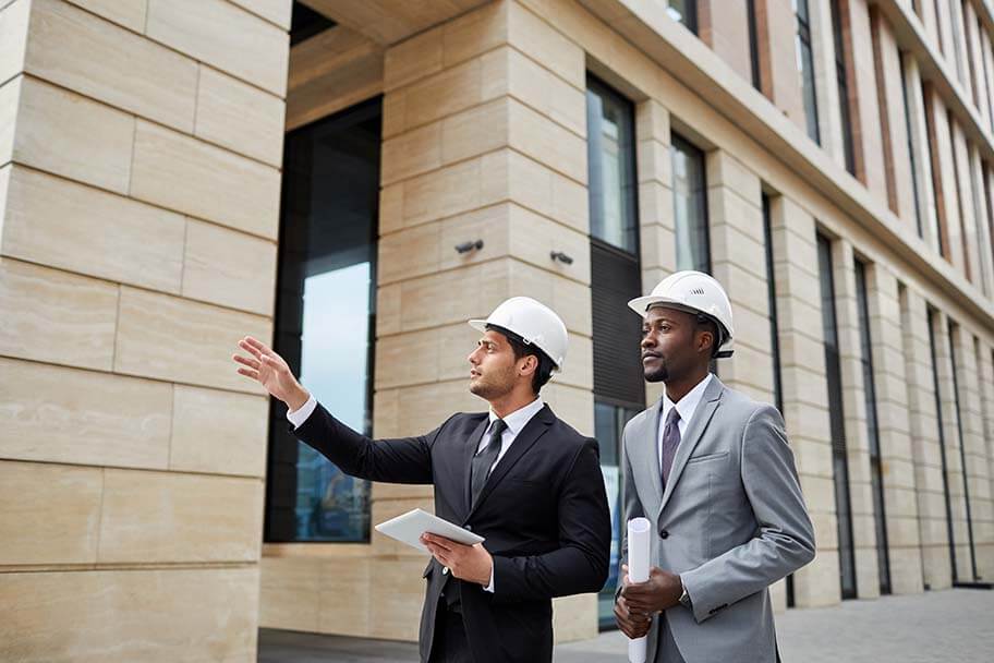 A person in a suit and a person in a white hat holding a paper