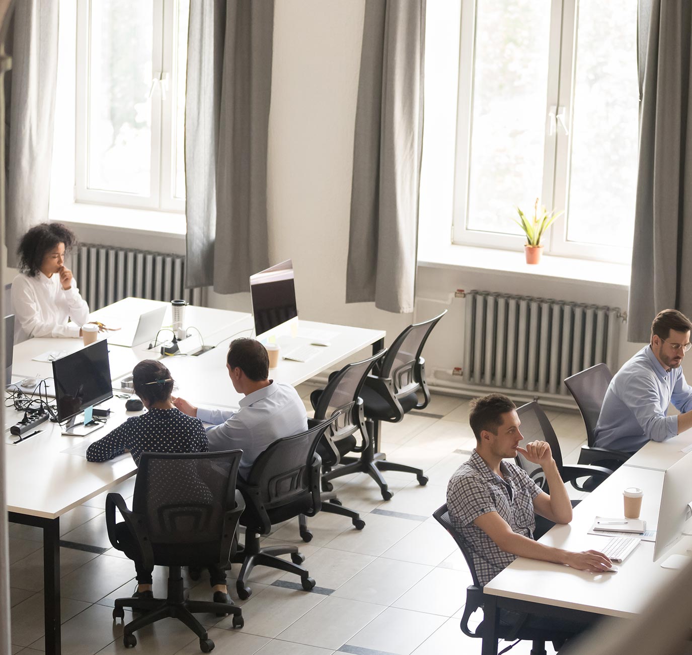 five people sitting at three rows of tables with computers