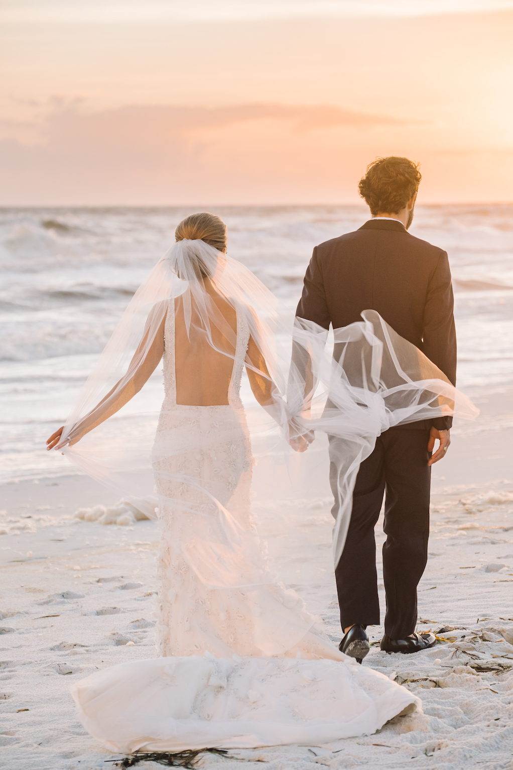 A bride and groom getting married on a white sand beach at sunset