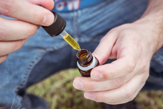 Person extracting a type of medical marijuana tincture out of a bottle