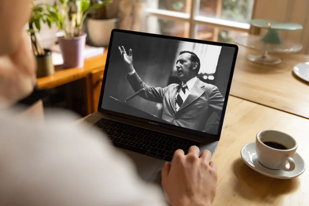 A man watching a Derek Prince sermon on his laptop