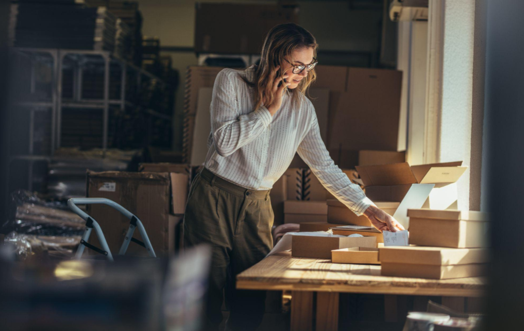 A busy woman, surrounded by boxes, on the phone with her insurance carrier