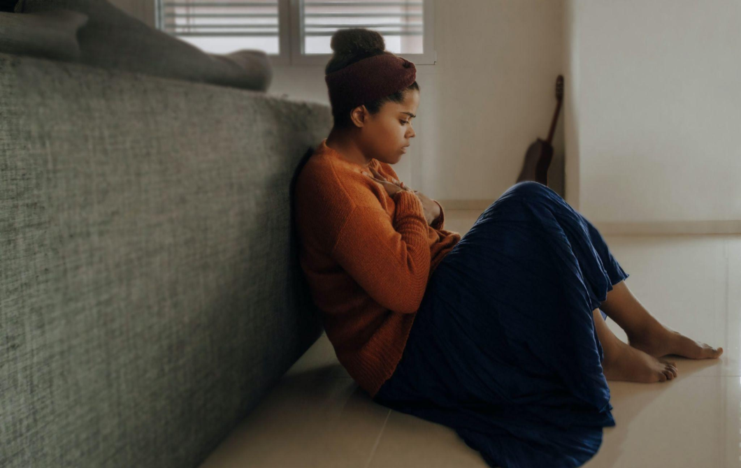 A woman sits on the floor in distress, wondering if she needs therapy