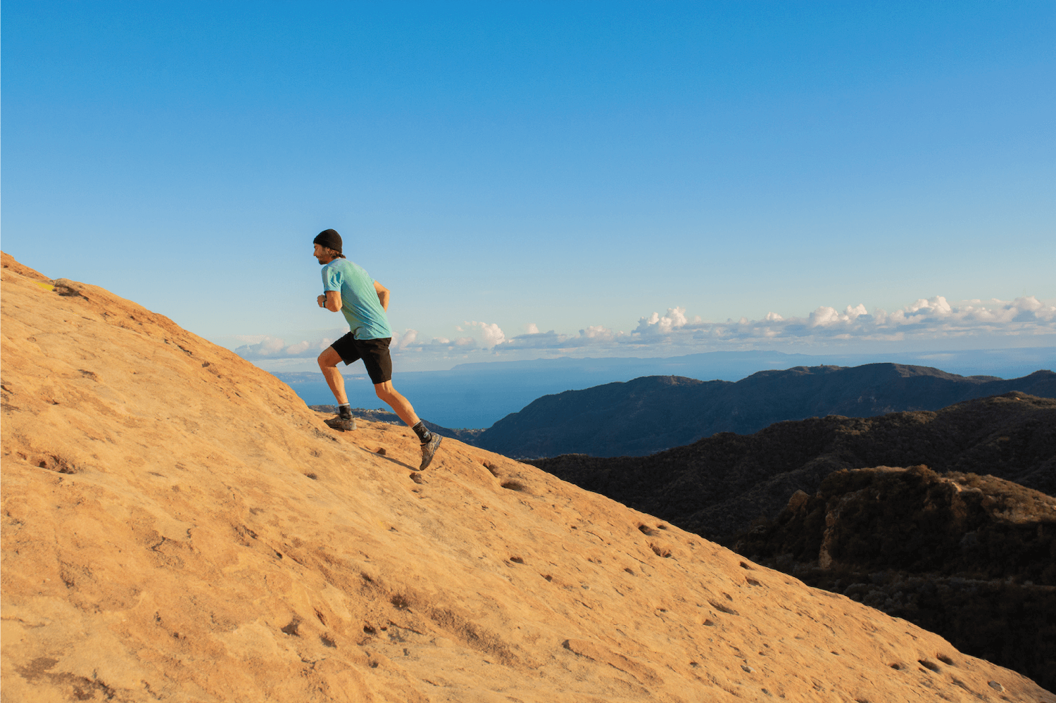 Man running up a sand dune at sunset