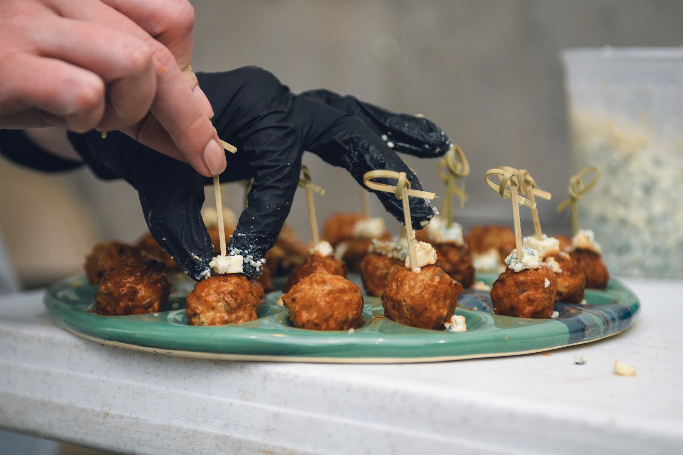 A person puts a toothpick through a meatball passed hors d'oeuvres