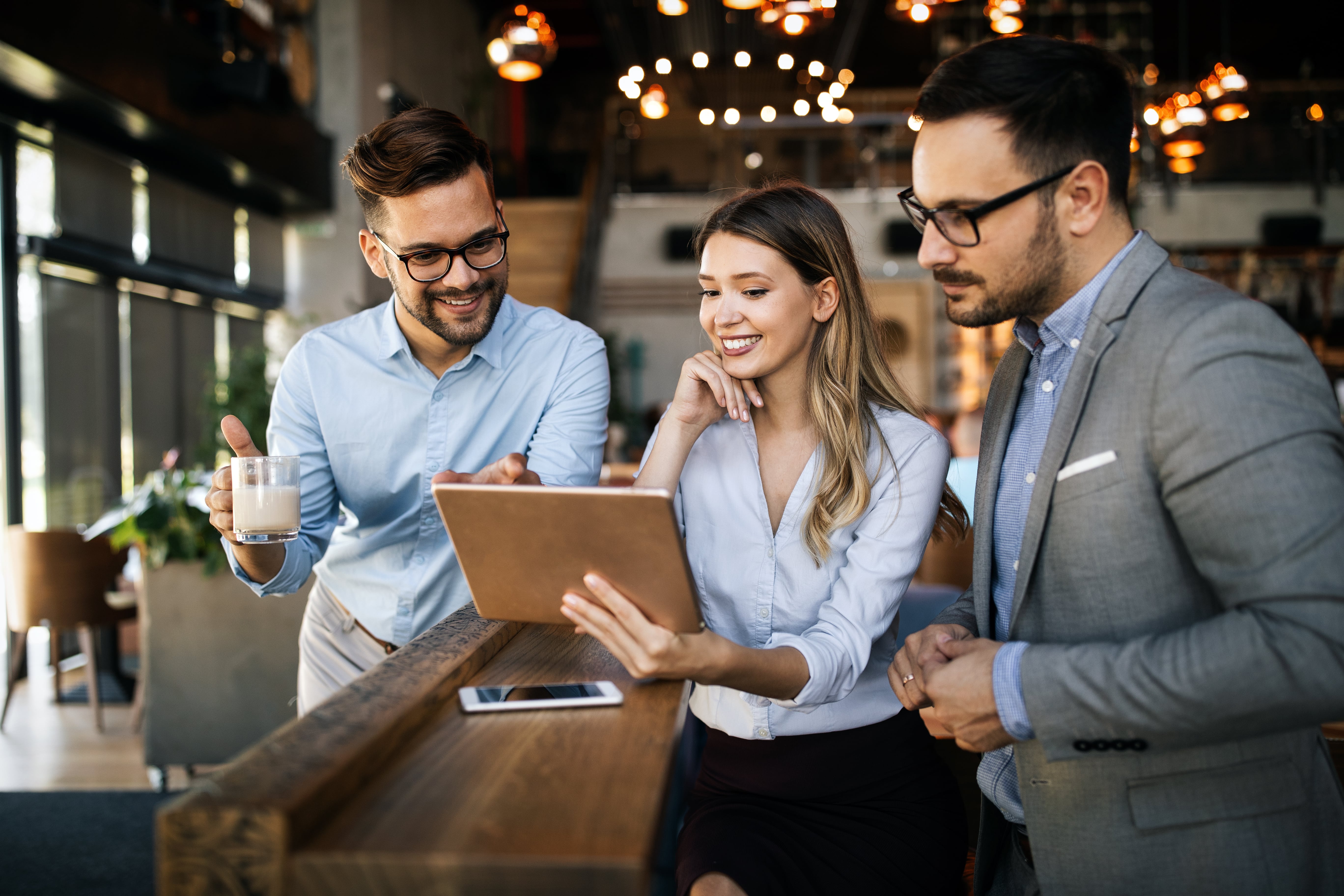 Three business people looking at a laptop in a coffee shop