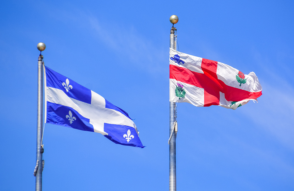 Drapeau du Québec et de la ville de Montréal flottant dans le ciel