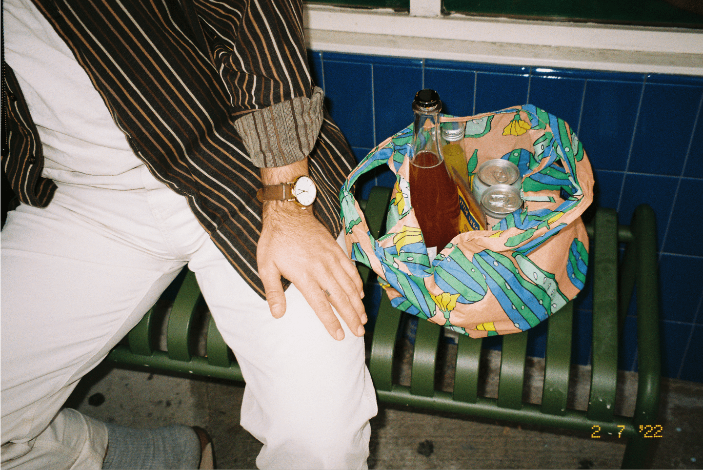 A person sitting on a bench with a bag of groceries