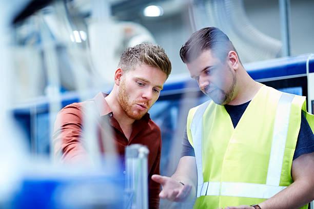 jeune homme travaillant dans manufacturing facility - consultant production photos et images de collection