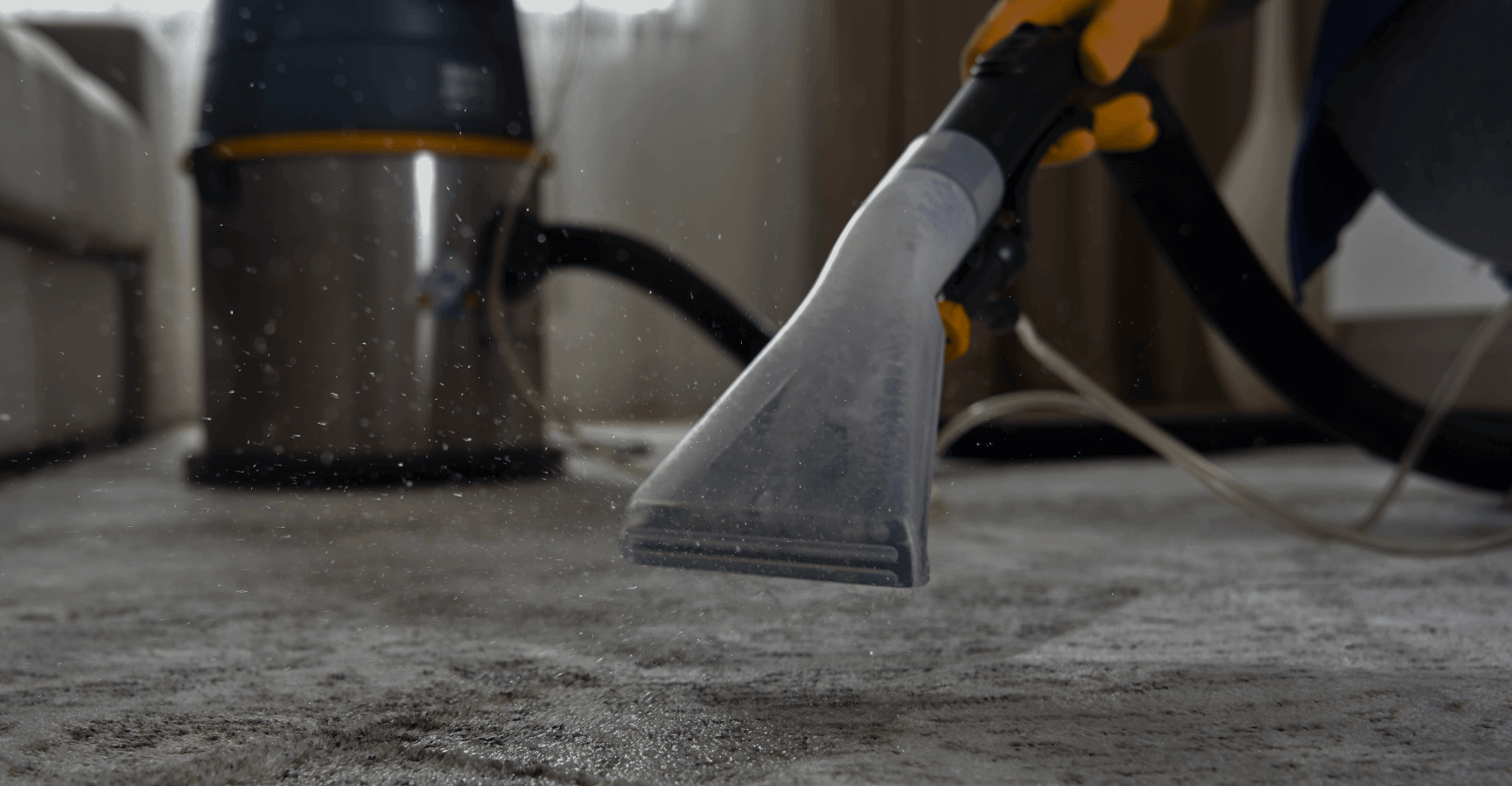 A picture of a SoCali Cleaners staff vacuuming dust from a white carpet.