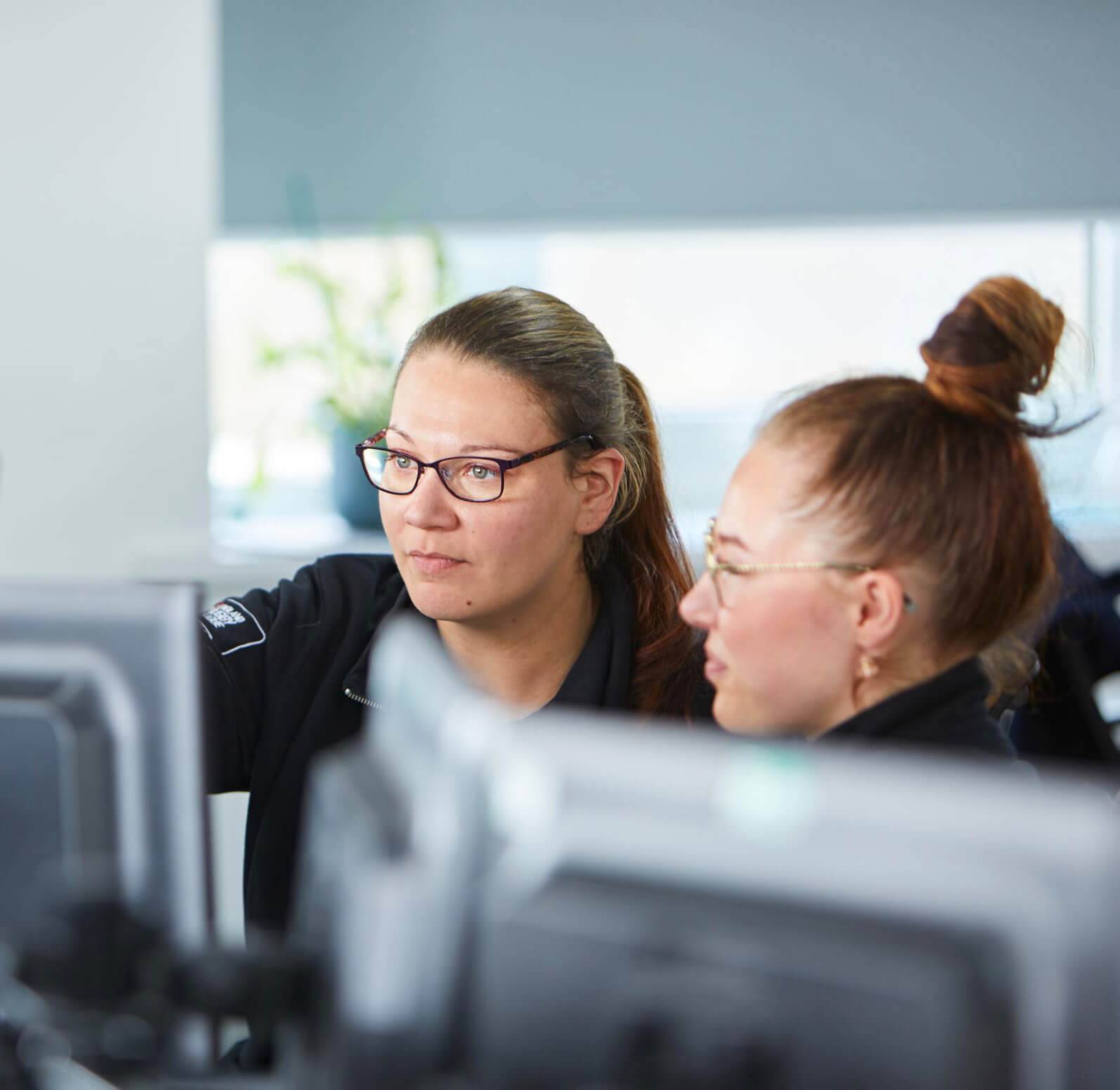 2 women sat together and looking at computer monitor