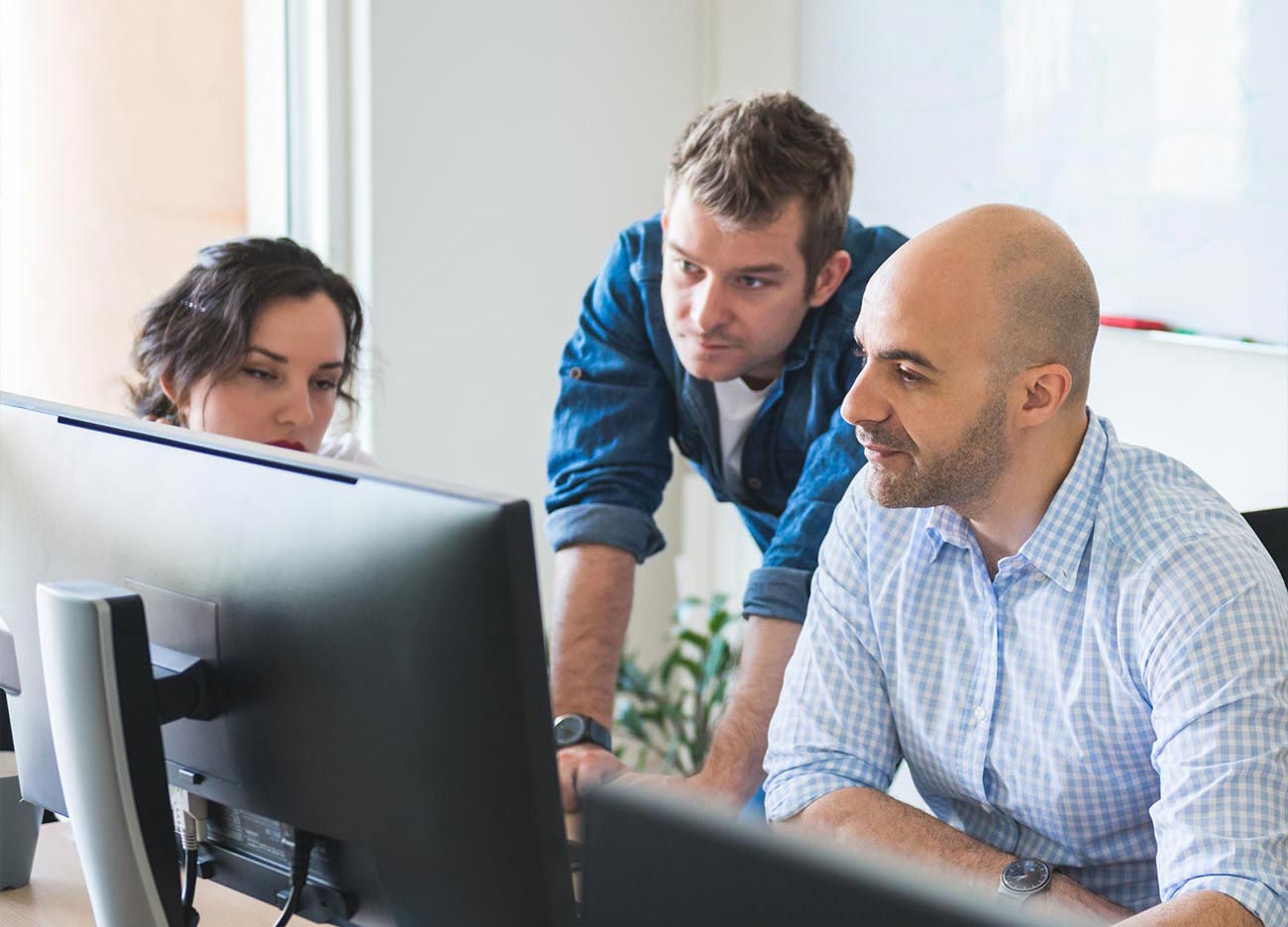 team collaborating while all looking at one computer screen
