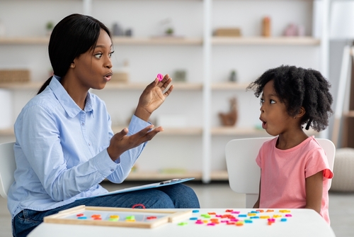 ABA Therapist works on speaking skills with a young girl.