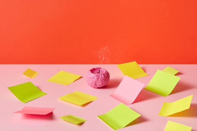 a candle shaped like a brain that is burnt out, surrounded by post it notes