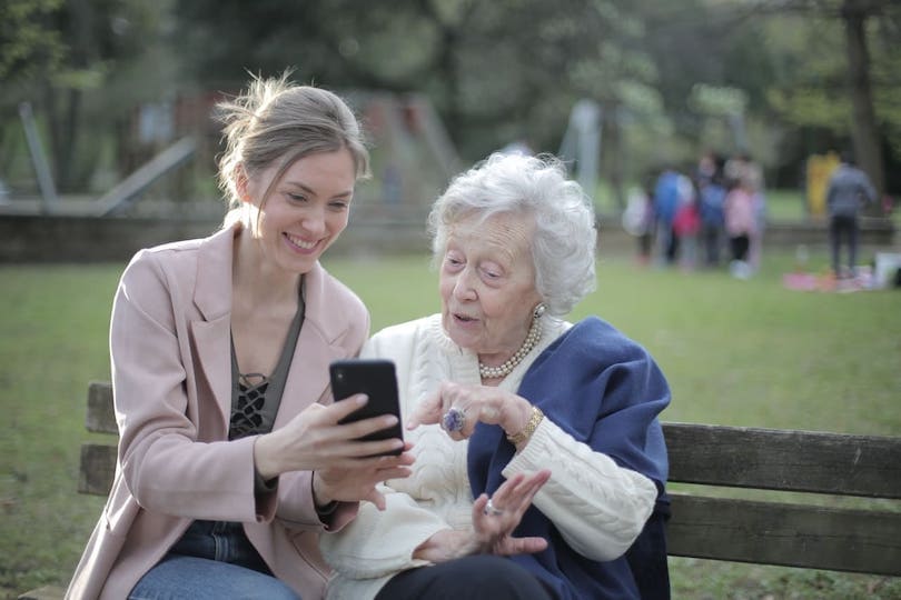 Enkelin und Oma werfen Blick auf digitale Pflegeanwendungen